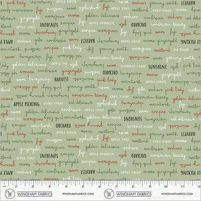 an image of green fabric with a pattern of rows of apple-related words in black, green, orange, and white