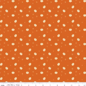 an image of orange fabric with a pattern of tossed cream colored pumpkins