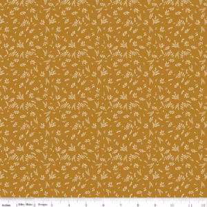 an image of golden brown fabric with a pattern of tossed sprigs of leaves