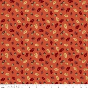an image of orange fabric with a pattern of tossed acorns and fall leaves