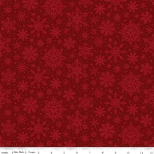 an image of red fabric with a pattern of tossed lighter red snowflakes