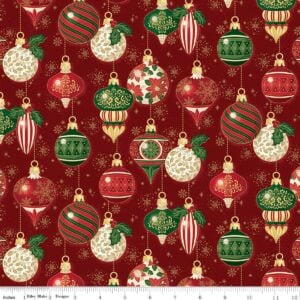 an image of red fabric with a pattern of round and oblong old fashioned tree ornaments in red and green with gold foil accents